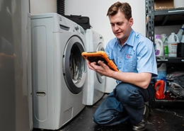 Mr. Appliance tech working on washing machine.