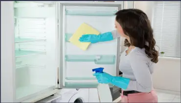 Lady cleaning the fridge.