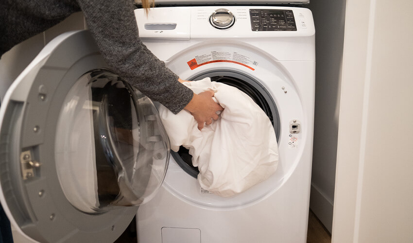 Hand putting sheets into dryer.